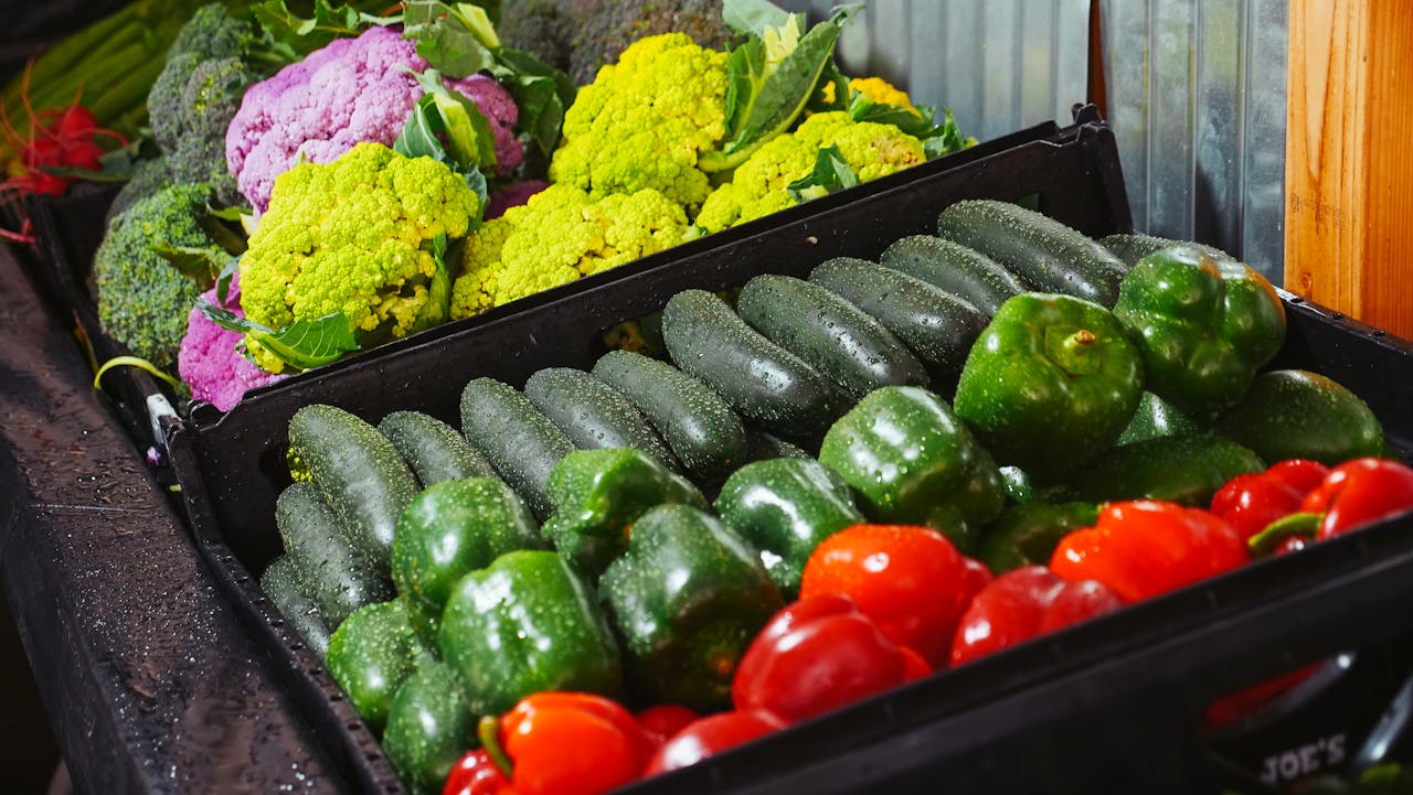 Colorful display of fresh vegetables including bell peppers, cauliflower, and zucchini at a market.